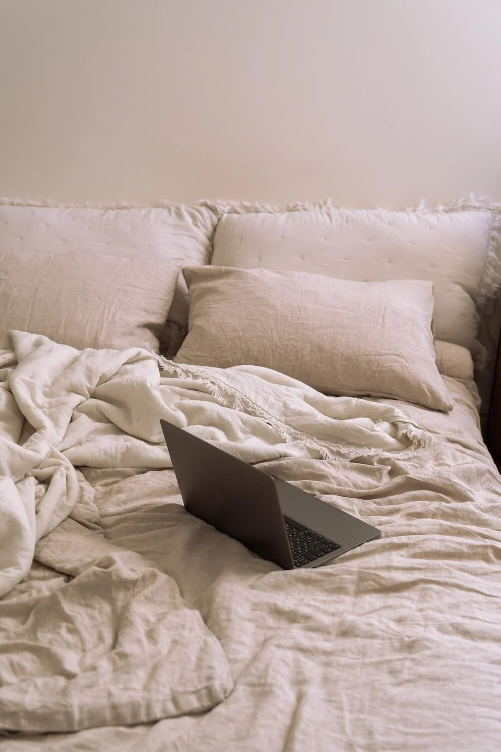 Laptop resting on an unmade bed