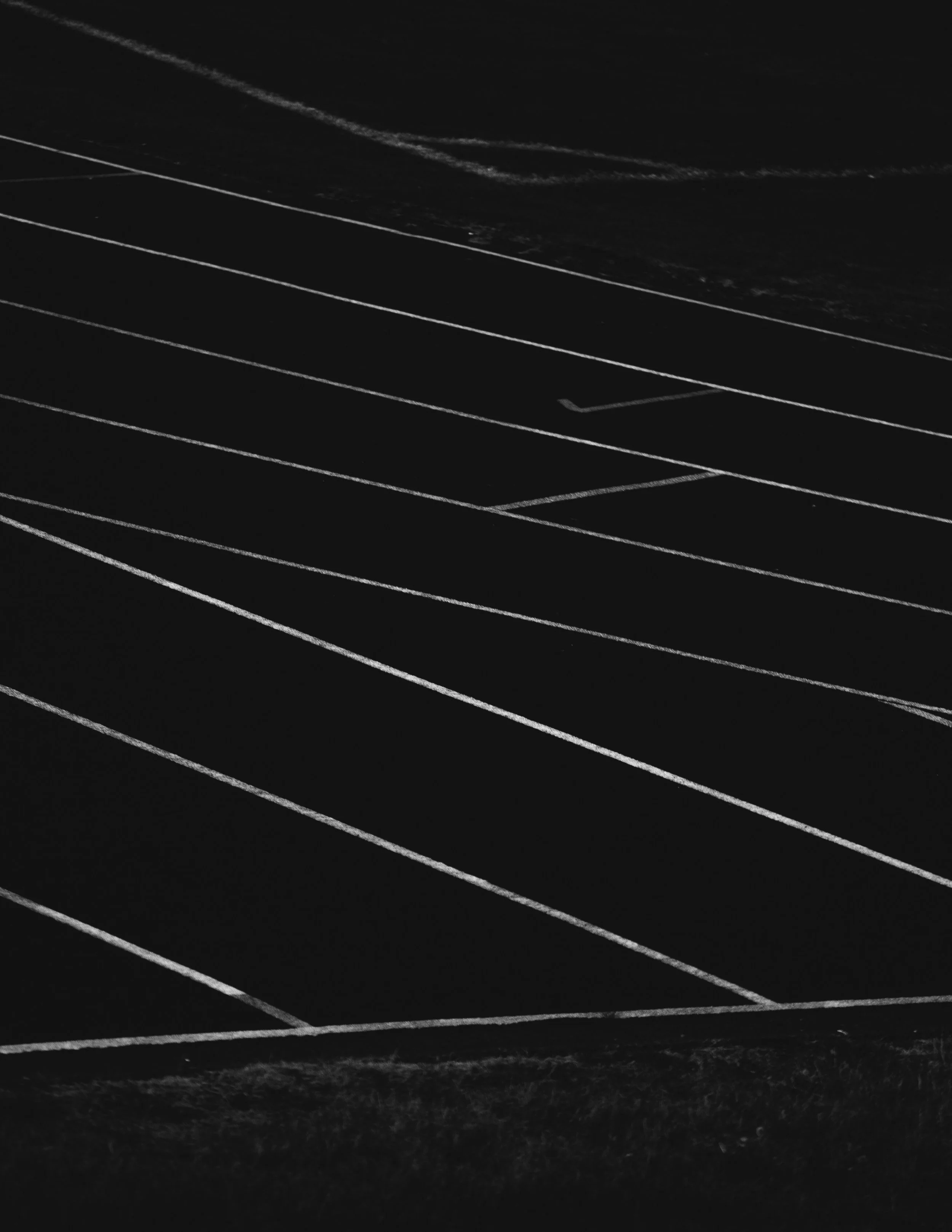 Dark running track with white lane lines at night, with some light reflecting off the surface.