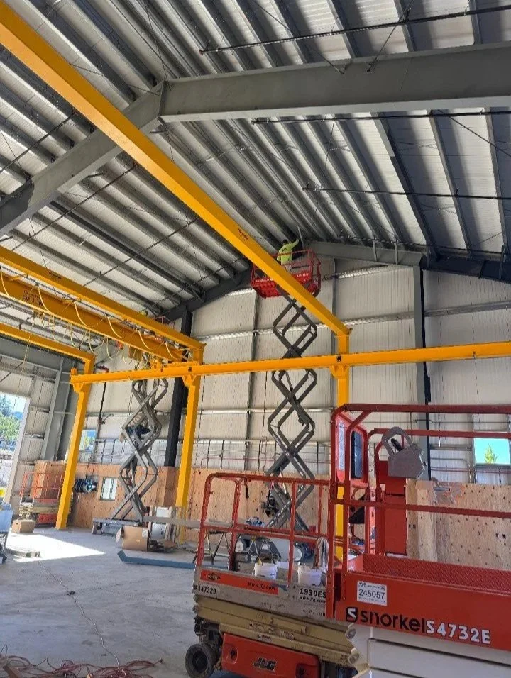 Construction workers on scissor lifts installing overhead steel beams in a building under construction.