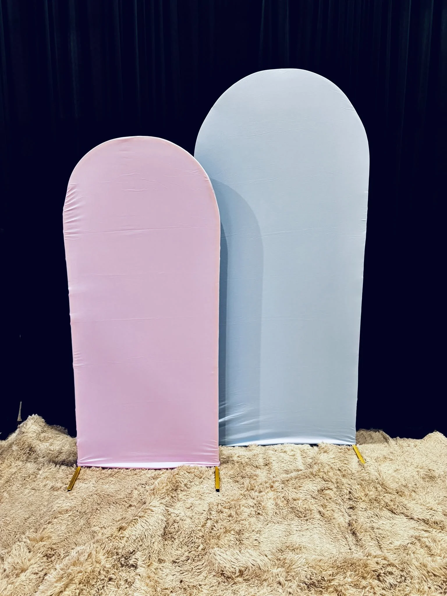 Two large padded room dividers, one pink and one light blue, standing on a beige shaggy carpet with a dark curtain backdrop.
