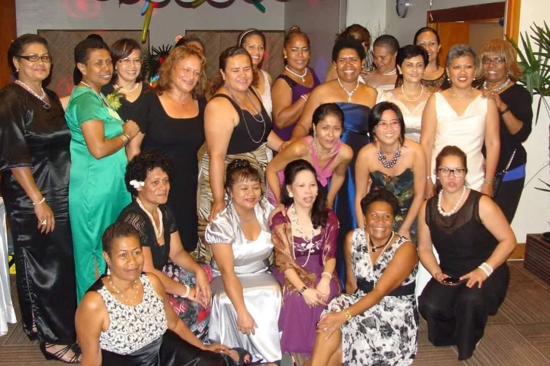 A group of women dressed in formal attire, posing for a photo at a celebration or party.