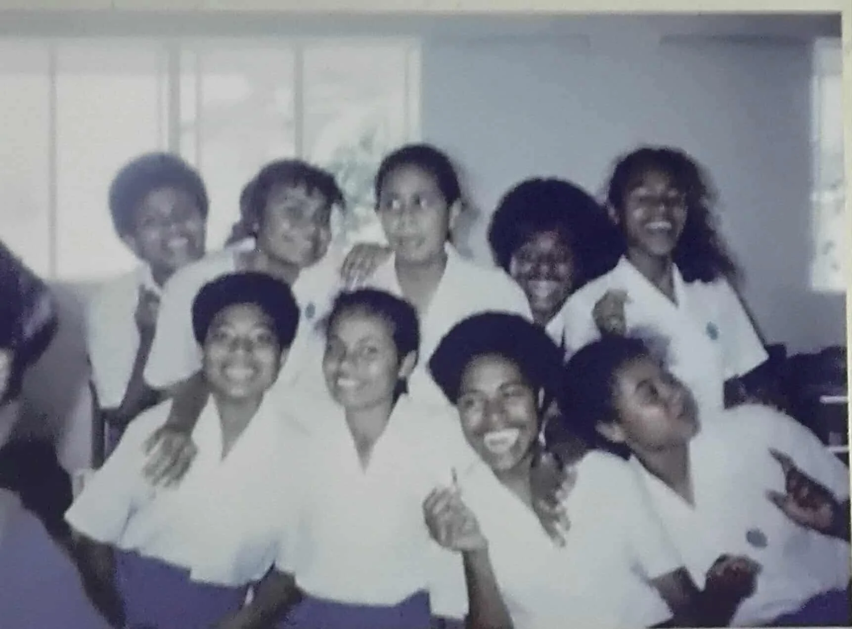 Black women wearing white uniforms celebrating together indoors.