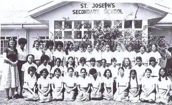 Group of students and teachers in front of St. Joseph's Secondary School building.