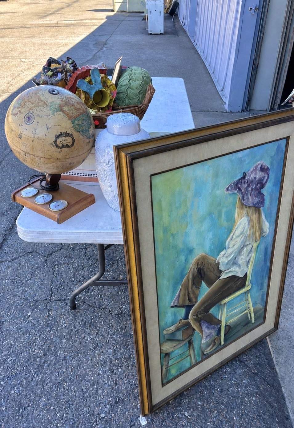Table filled with estate-sourced jewelry, ceramics, clocks, postcards, frames, and small decorative objects.