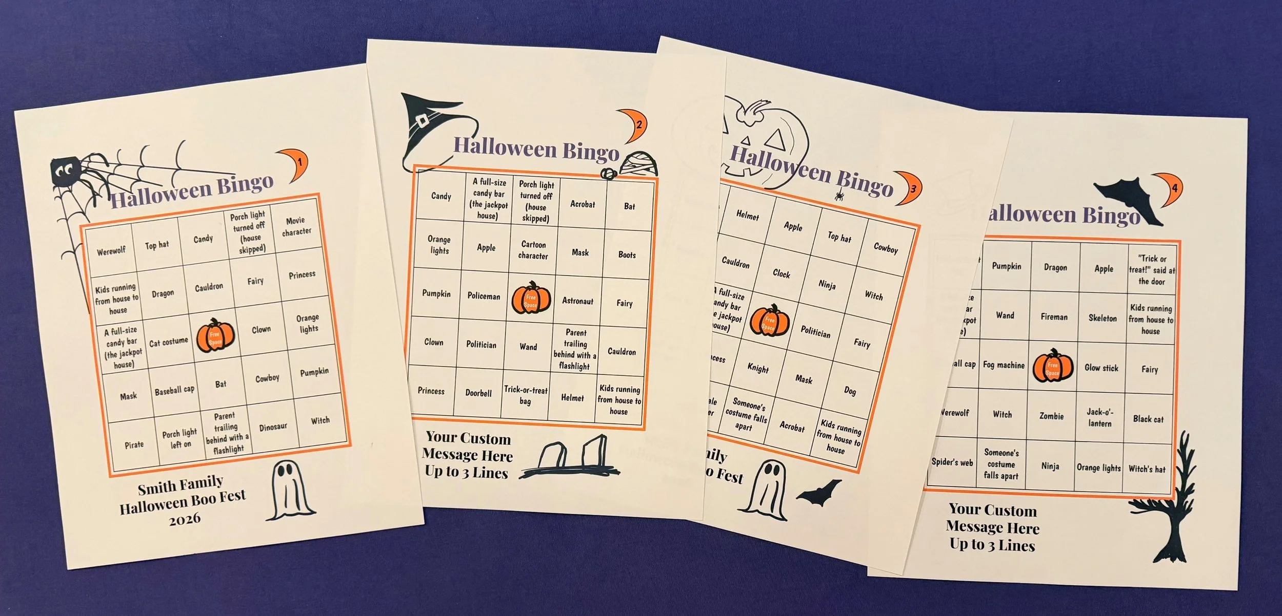 Four Halloween-themed bingo cards with various spooky words and images, including a spider, ghost, bat, and pumpkin, on a purple surface.