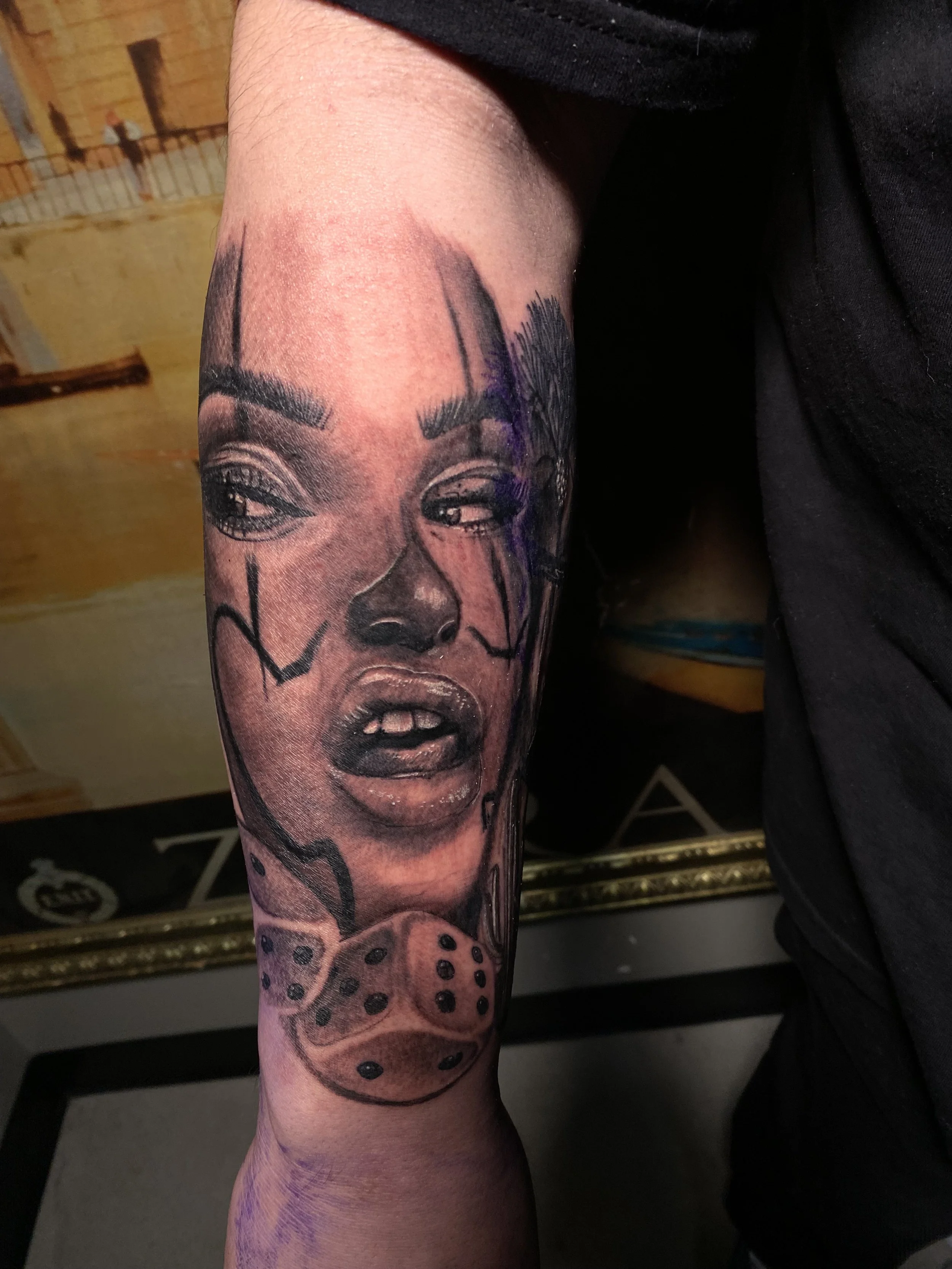 Close-up of a person's arm with a tattoo of a woman's face and a cheetah's face on the forearm.