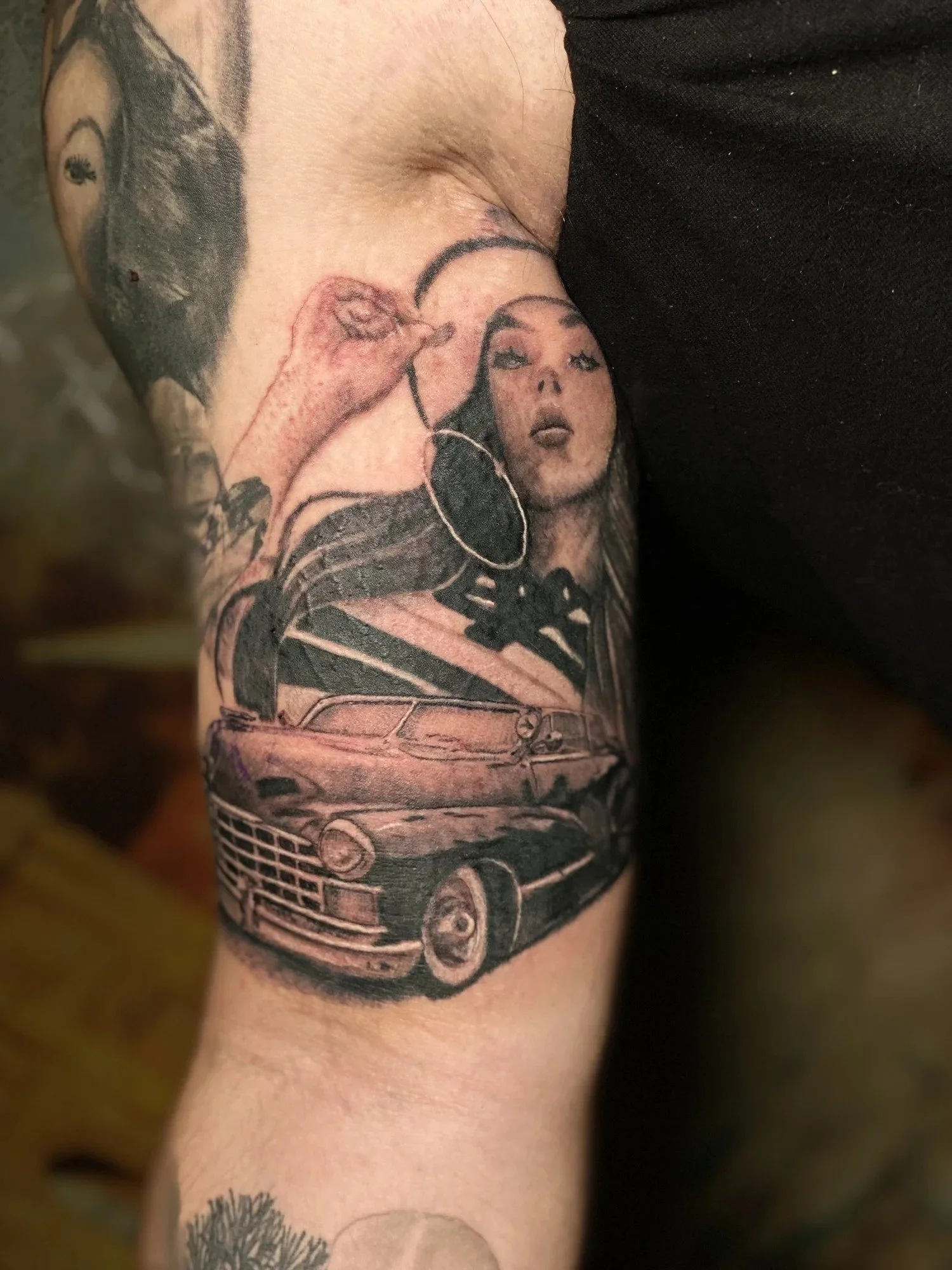 Black and grey realism tattoo of a woman and lowrider car on a forearm by Esteban, San Diego tattoo artist