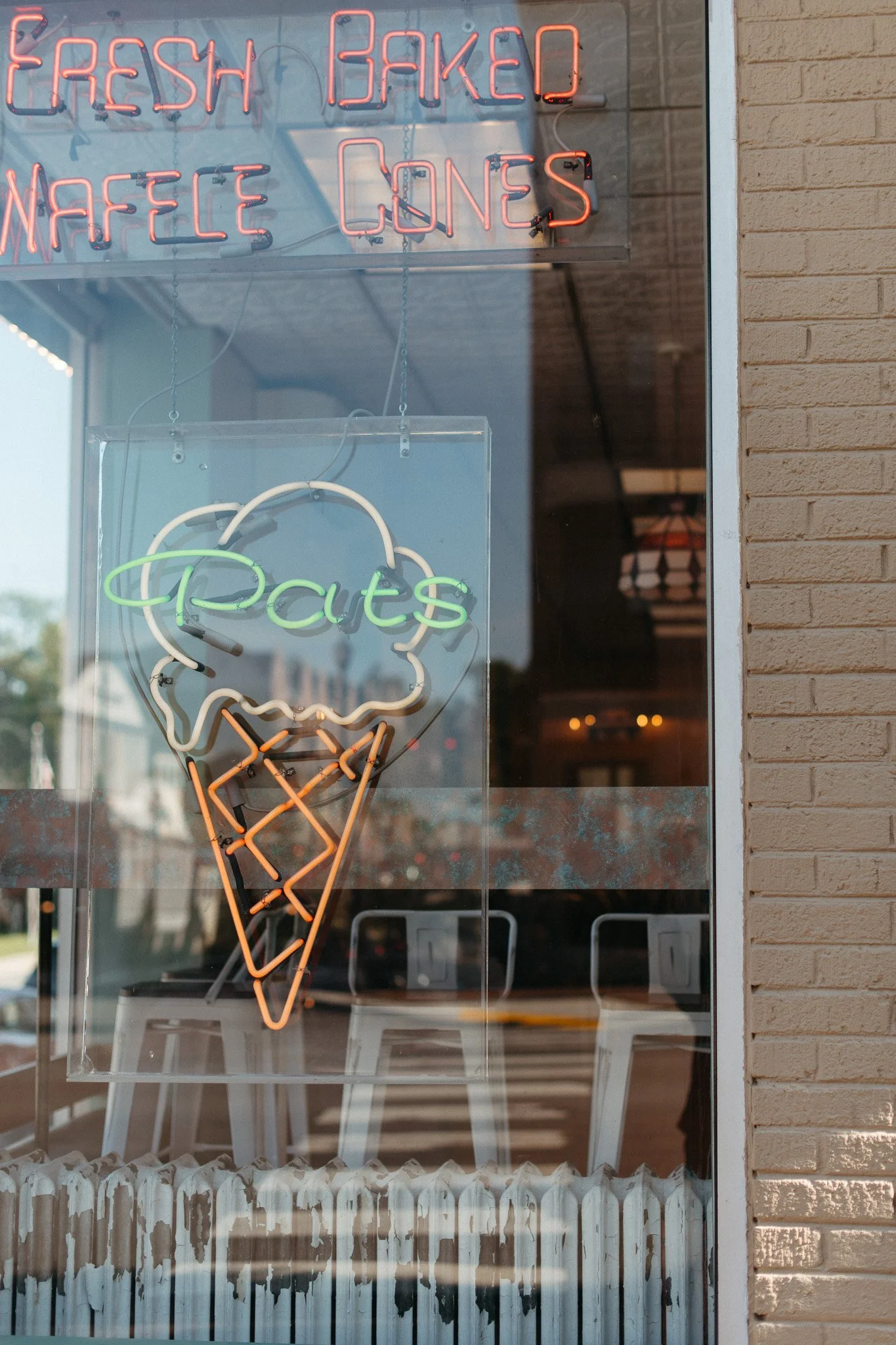 Neon sign outside a restaurant displaying the words 'Fresh Baked Waffle Cones' and an ice cream cone icon.