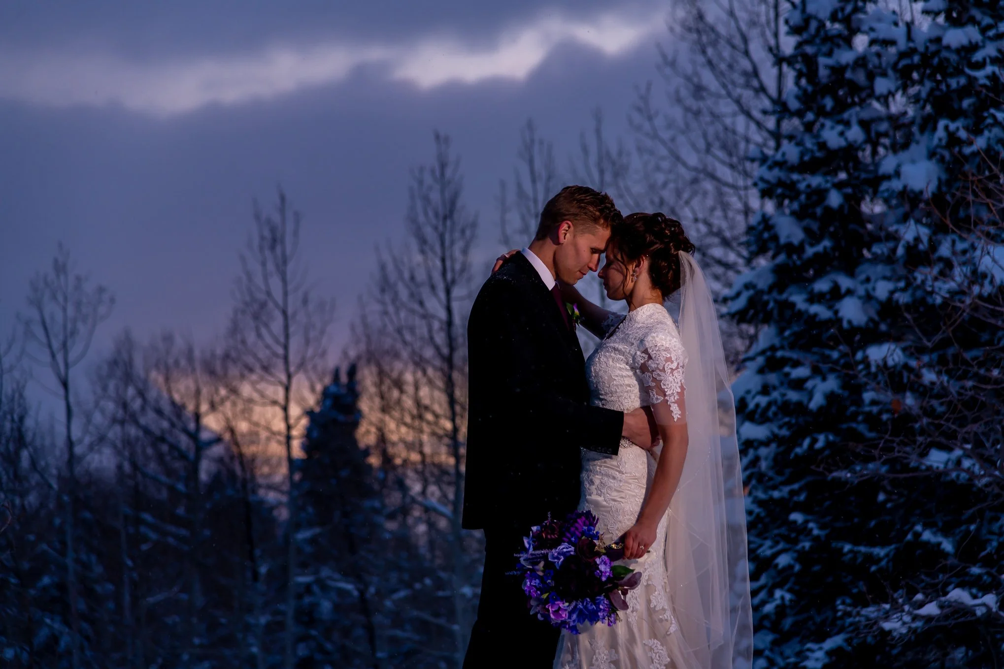 Snowy, stormy embracing bride and groom in Little Cottonwood Canyon in the winter snow