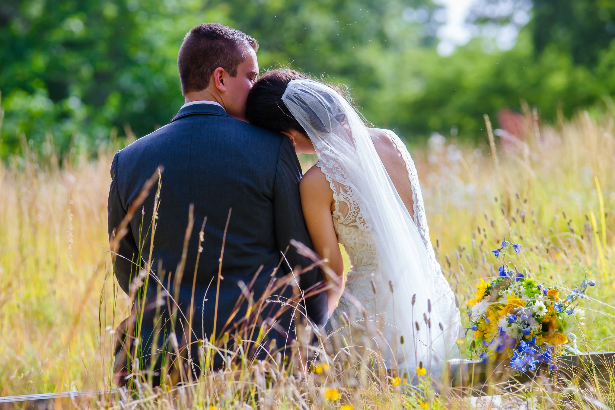 Bride and groom snuggle in field of wildflower at Red Butte Garden wedding