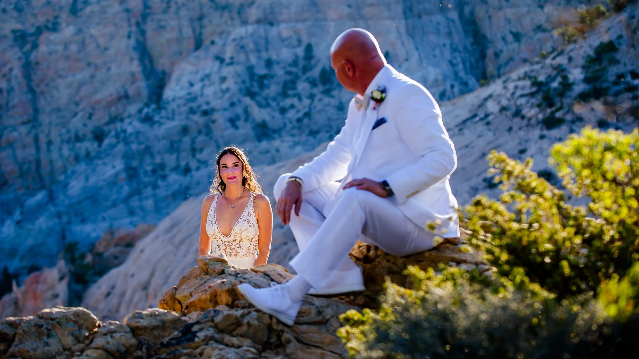 Devils Backbone wedding ceremony.  Groom sits admiring his bride who is glowing from the sun's reflection on the cliff her groom sits.