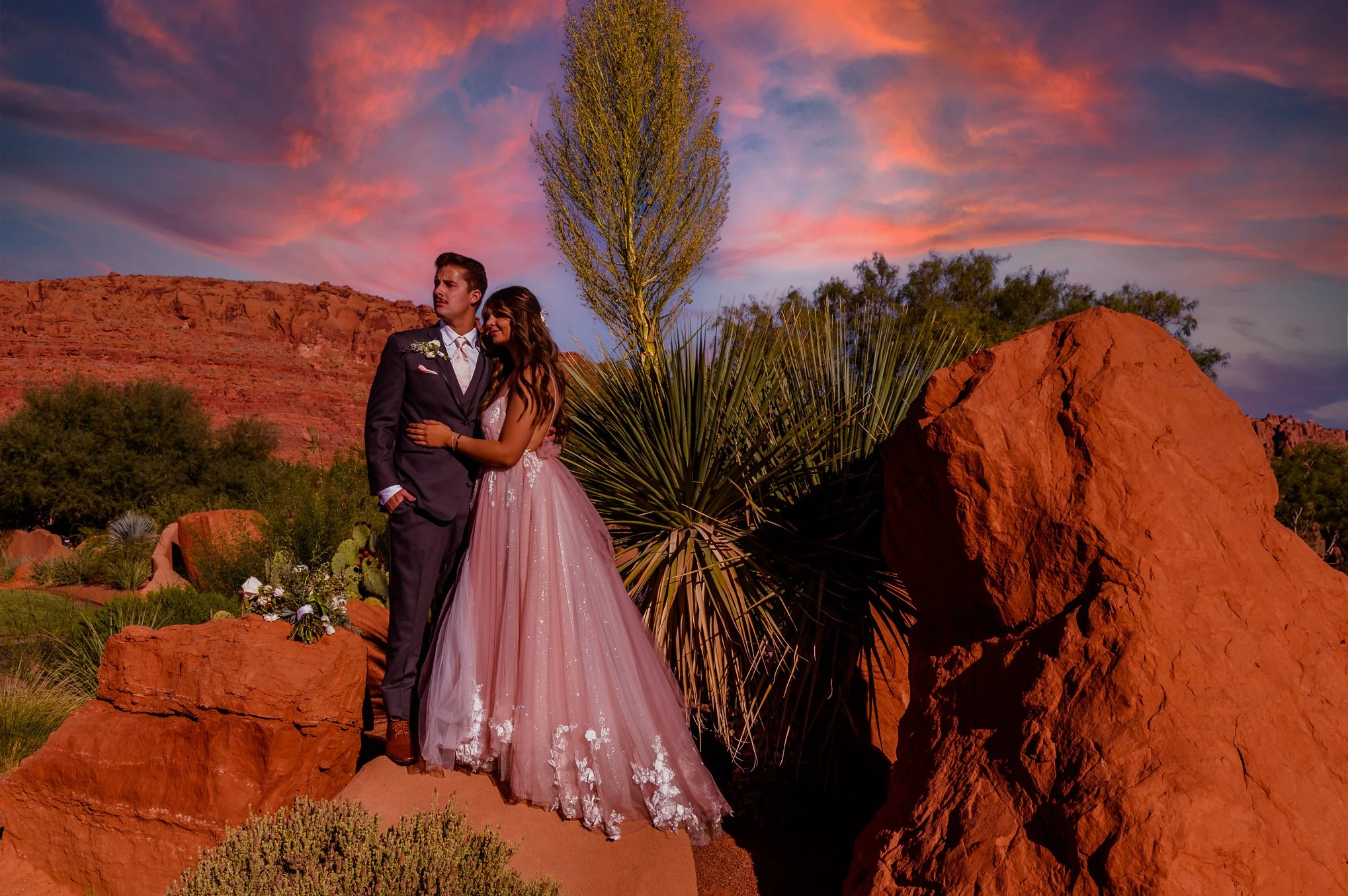 Bride and groom at Entrada in Southern Utah.  Pink wedding dress, pink skies, red rock