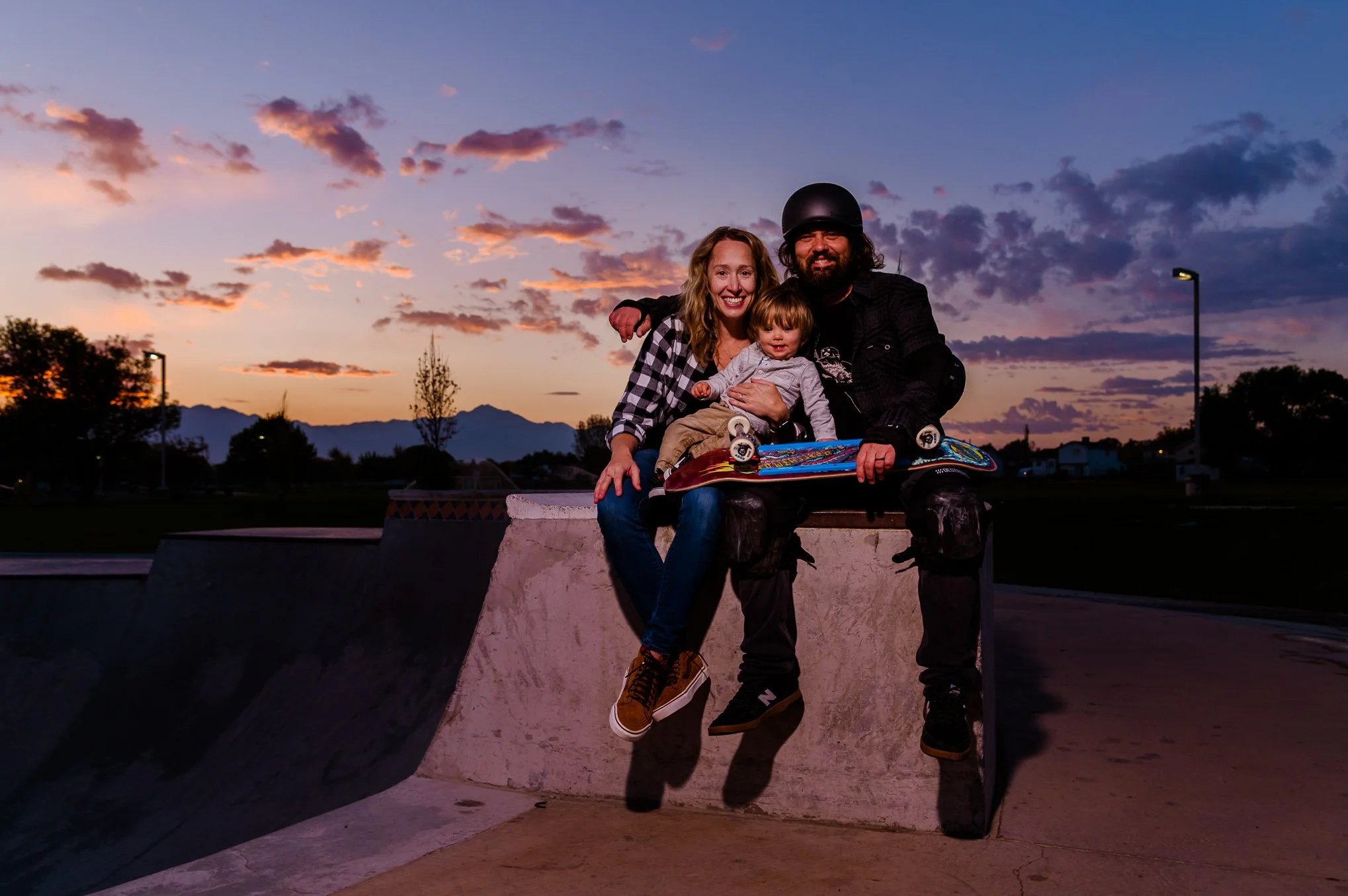 a family of 3 pose for a portrait at sunrise before a skateboarding session