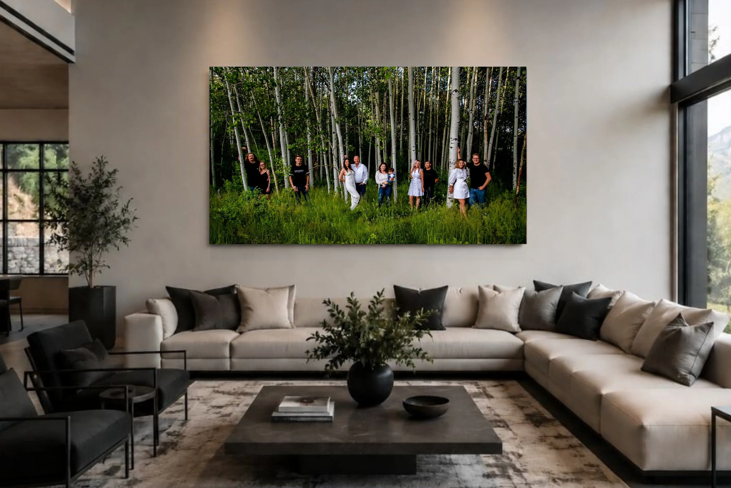 Modern living room with beige sectional sofa, black armchairs, coffee table, and large abstract wall art of a forest with people walking among trees.