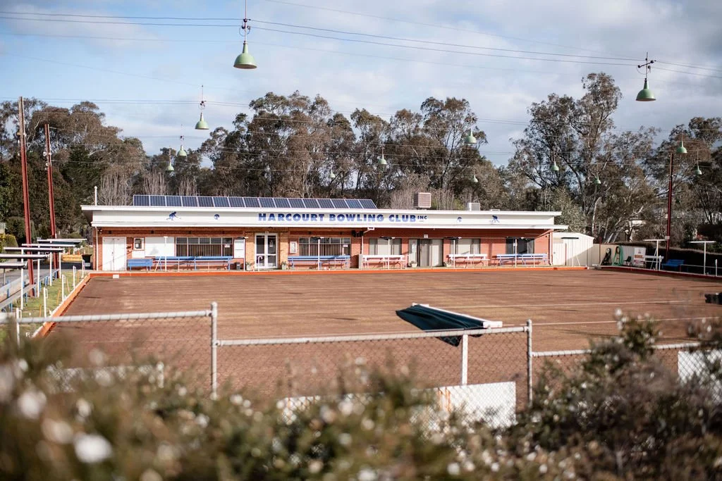 Empty outdoor bowling green at Harcourt Bowling Club with building in background and trees behind
