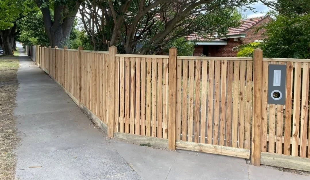 Wooden fence along a sidewalk in a residential neighborhood.