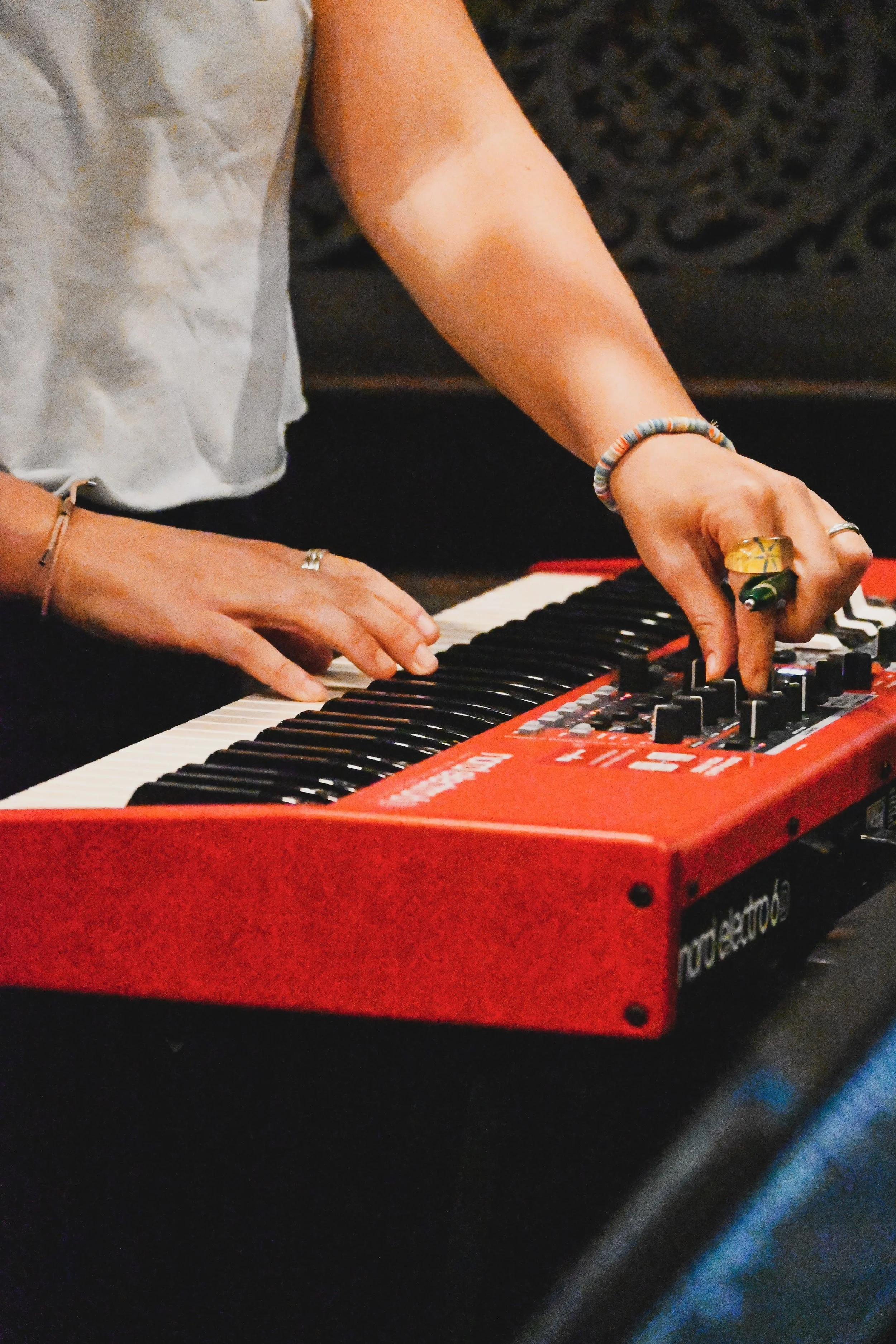 Close-up of a student playing a red Nord Electronic keyboard during a band rehearsal at Red House Music and Rehearsal Studio.