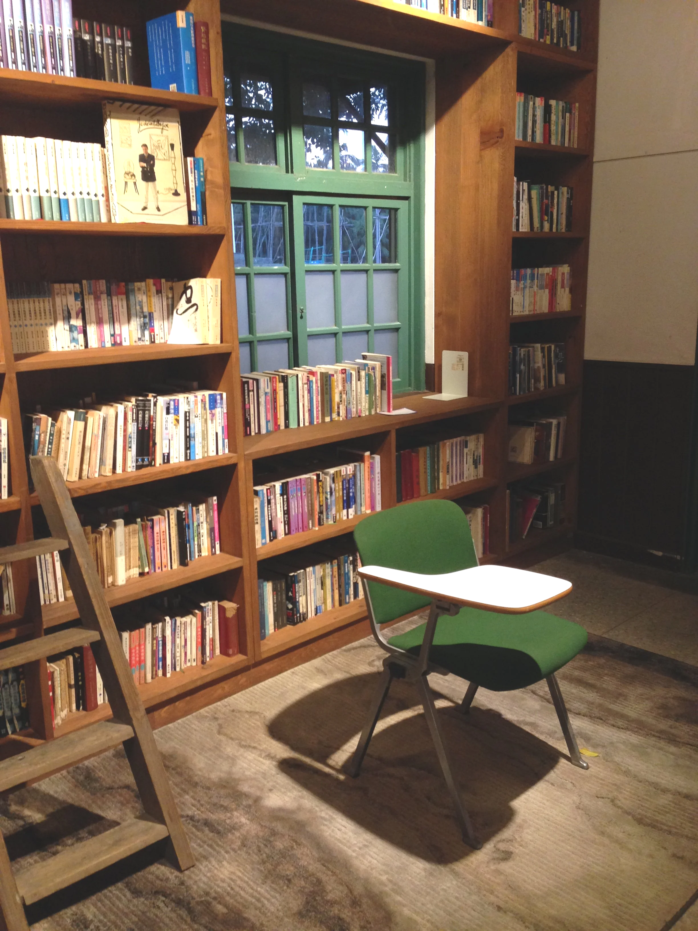 Bookshelves full of books behind a green chair