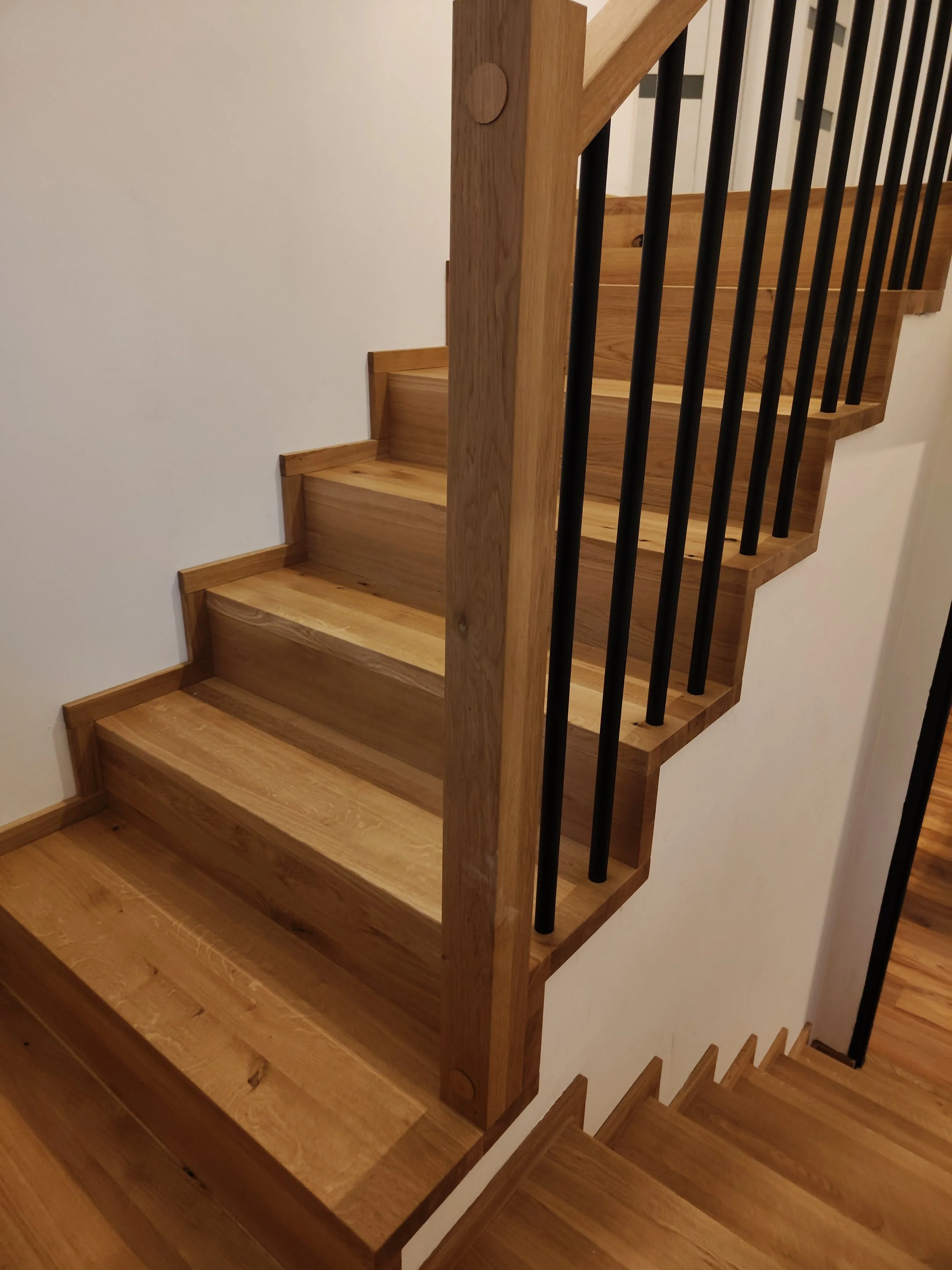 Wooden staircase with black metal balusters in a home interior.