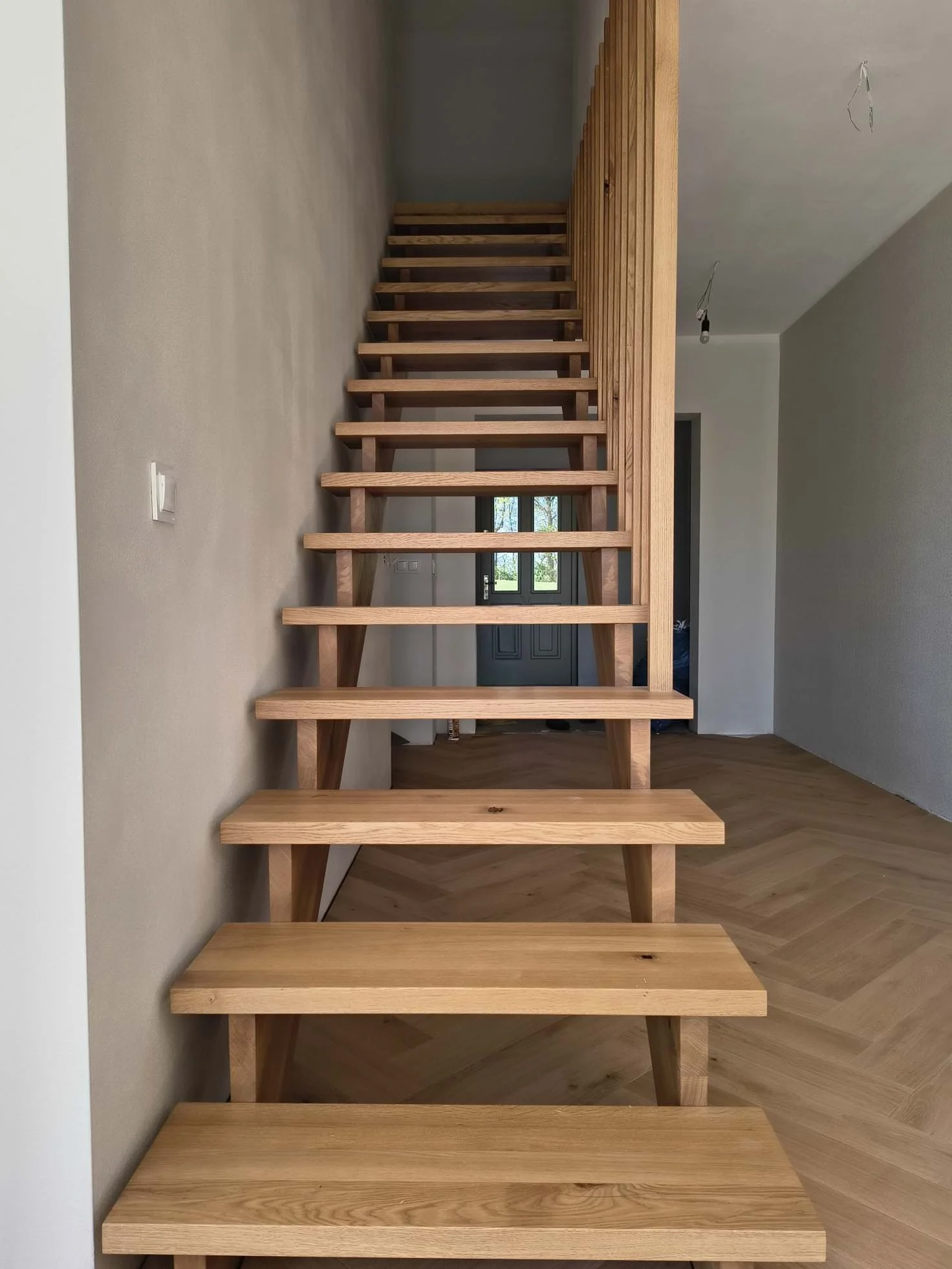 Unfinished wooden staircase with no railing, leading to an upper level in a modern home under construction.