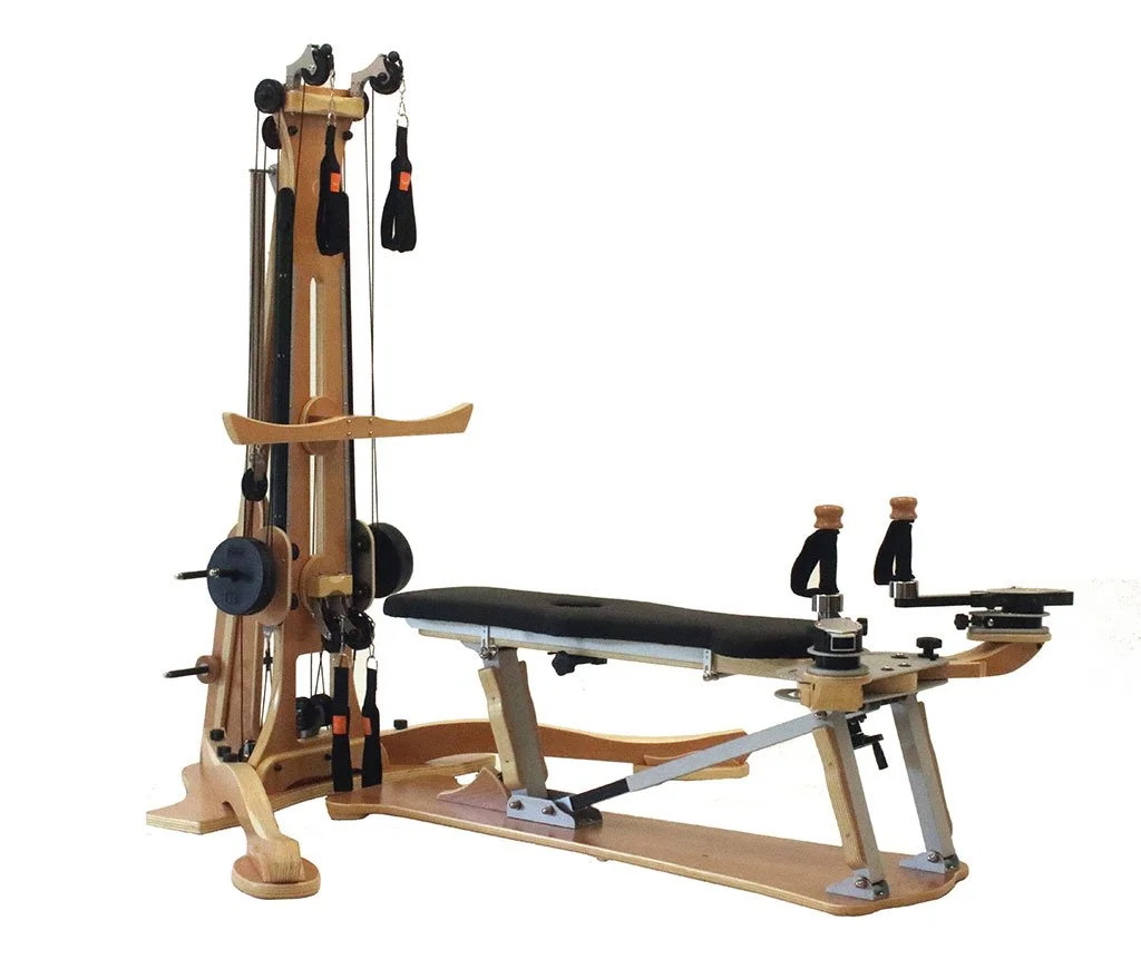 Wooden Gyrotonic Pulley Tower machine with black padded bench, pulleys, and adjustable straps.