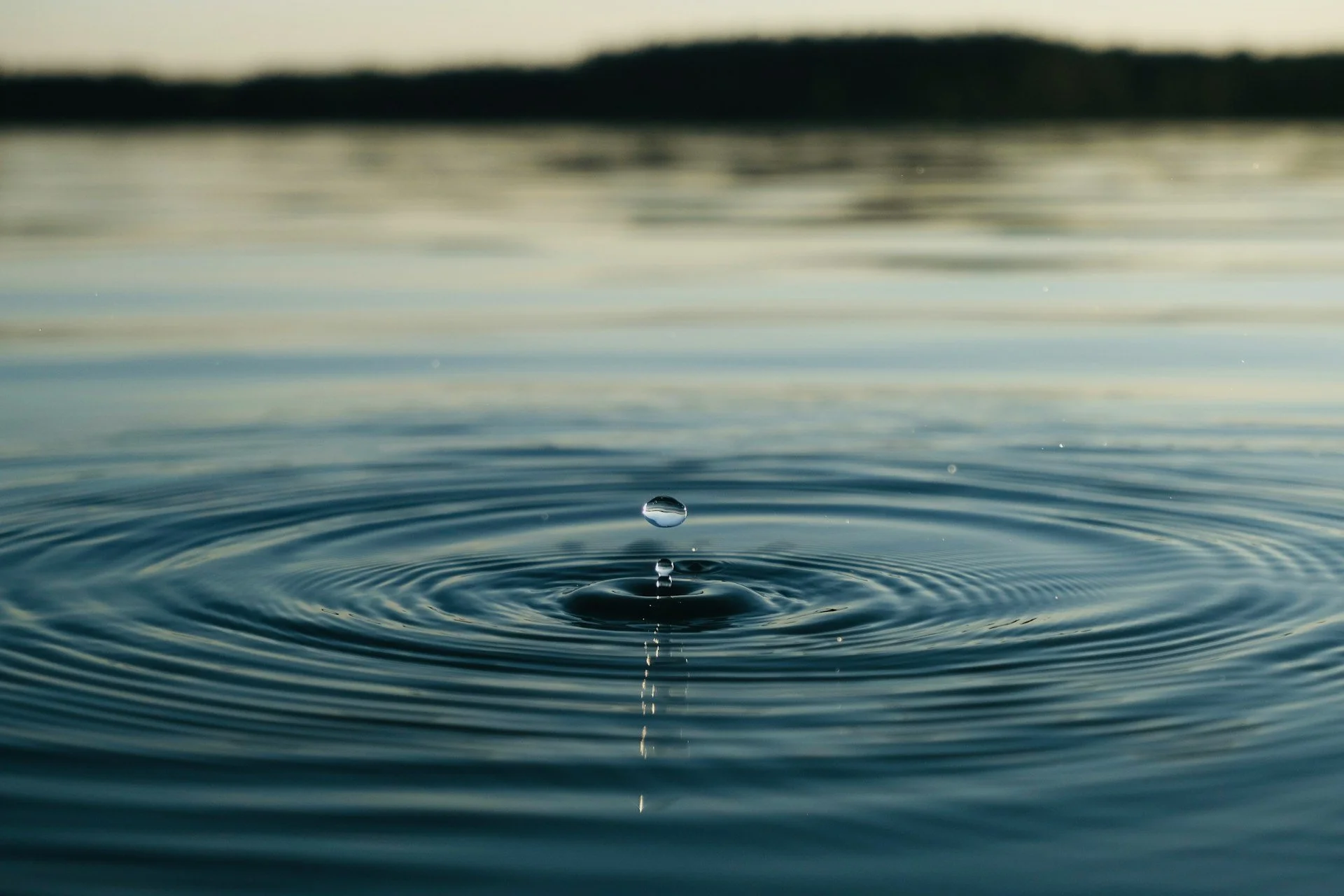 droplet falling into a large body of water creating a ripple effect