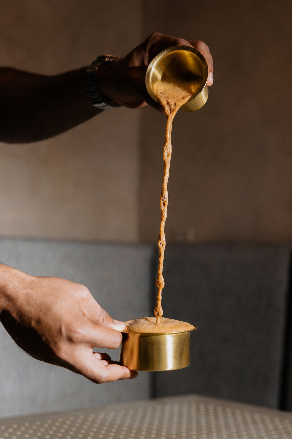 Traditional South Indian filter coffee being poured into a stainless steel davara at Veda in Kitsilano, Vancouver.