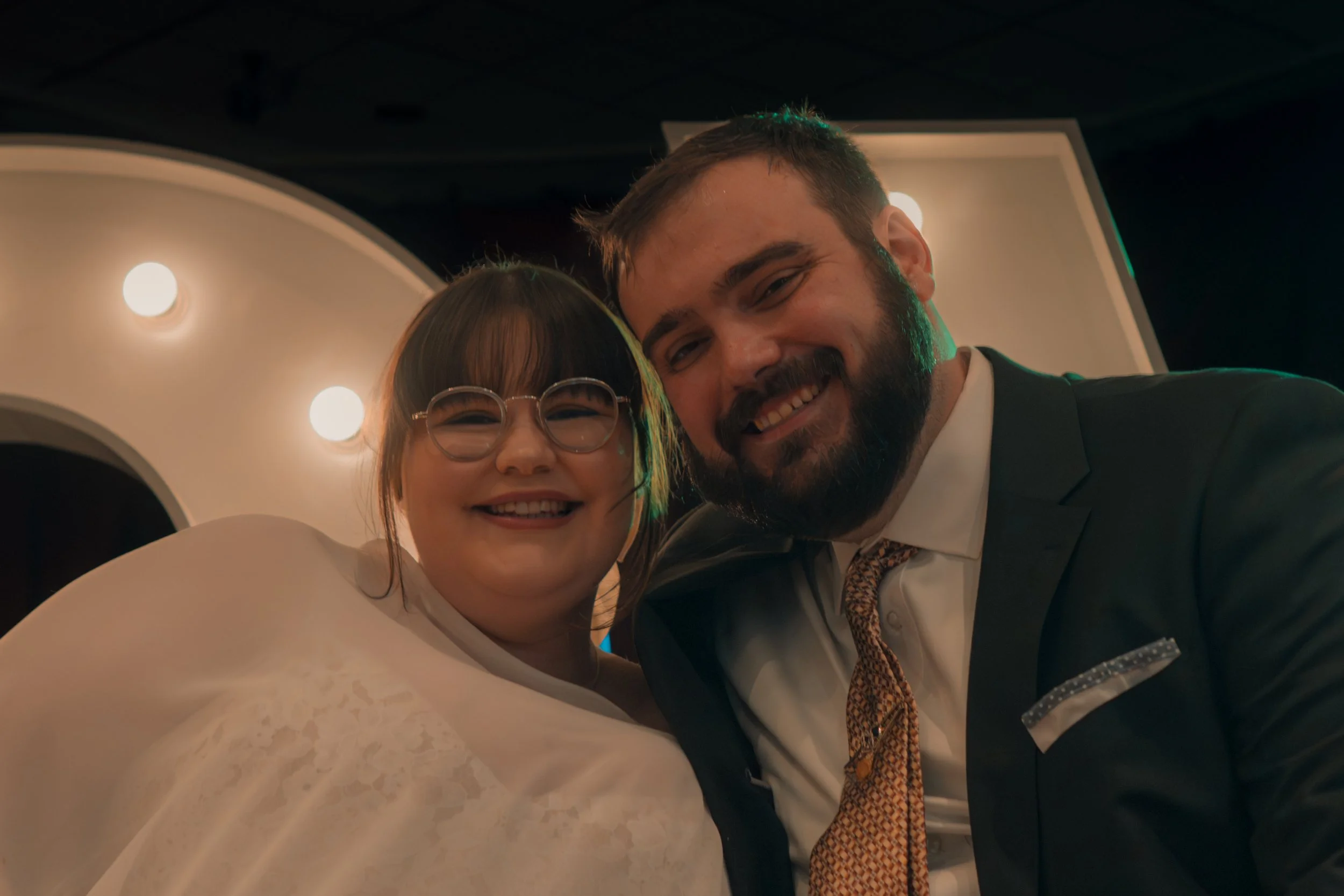 A man and young girl smiling and taking a selfie together indoors.