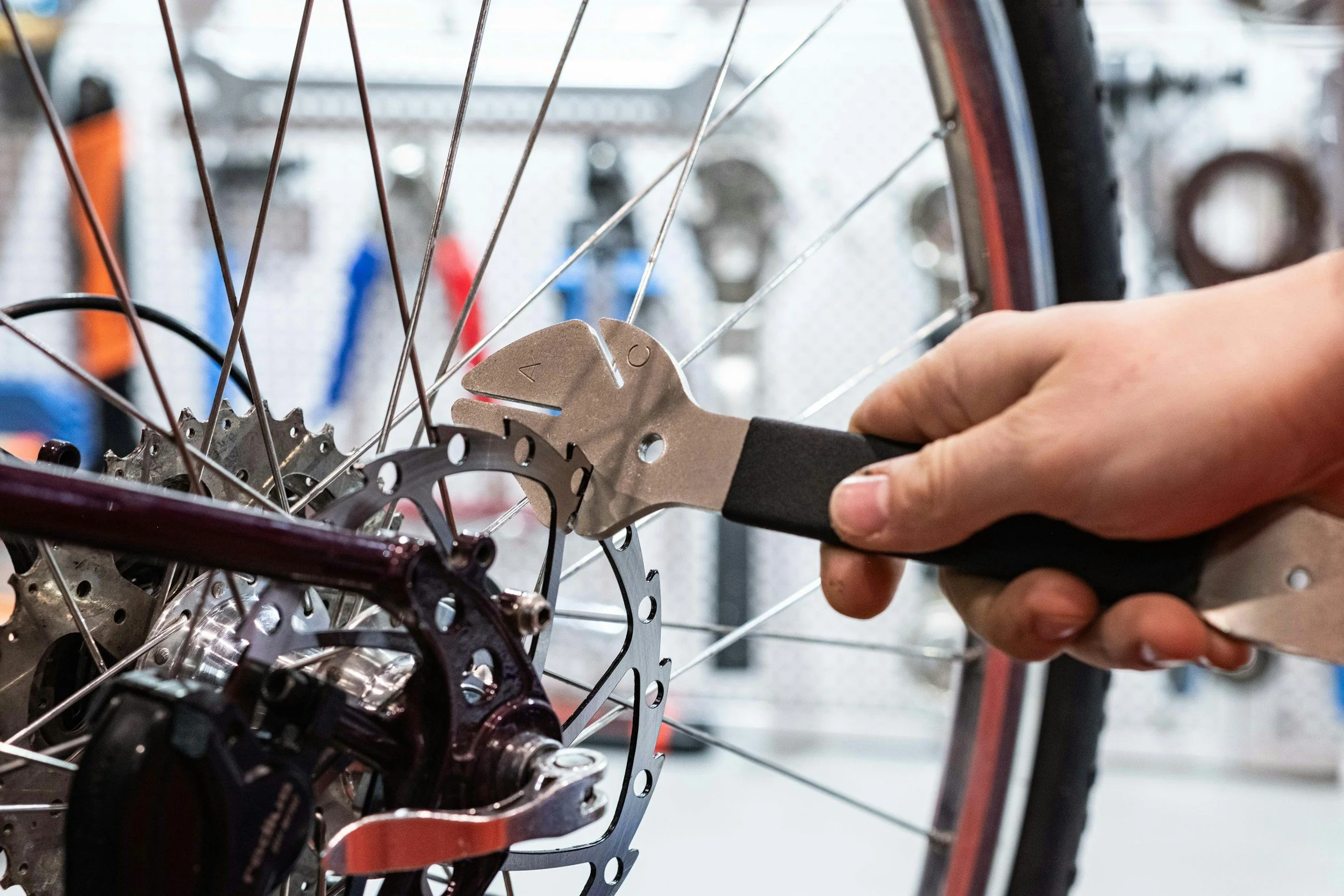 Close-up of a bicycle mechanic using adjustable pliers to repair a wheel and disc brake