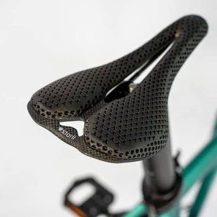 Close-up of a black perforated bicycle saddle on a teal bike