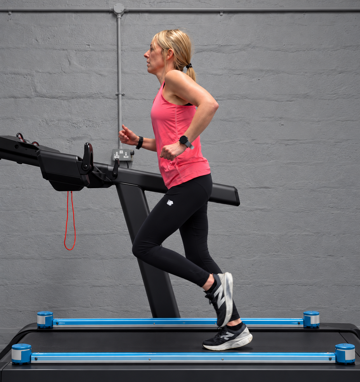 Woman in pink athletic top jogging on a curved treadmill in a gym