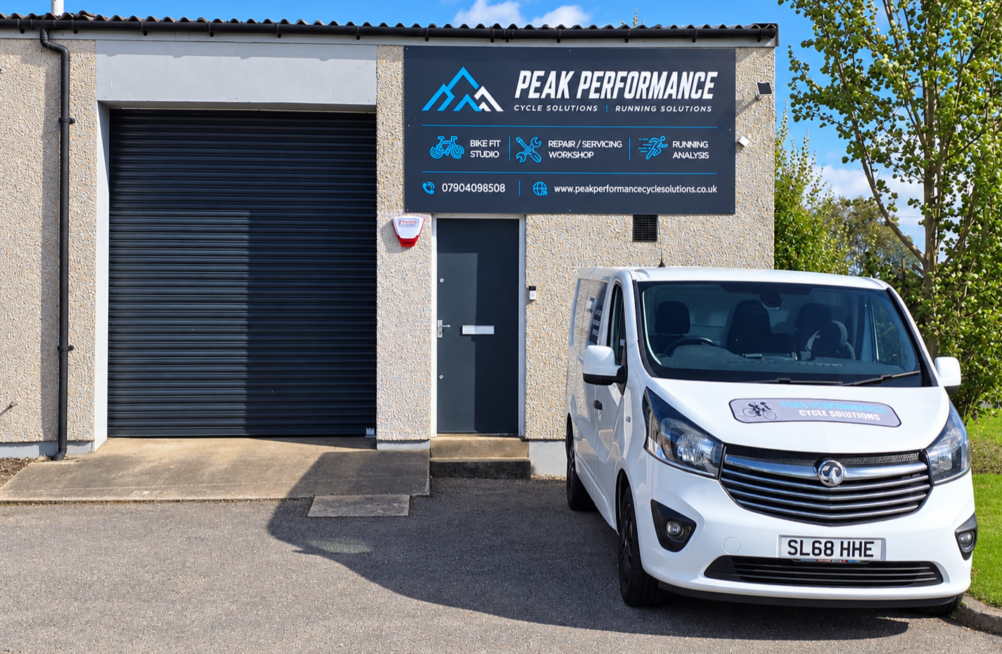 Peak Performance Cycle Solutions workshop exterior with a branded white service van, bike fitting studio, repair workshop, and running analysis signage