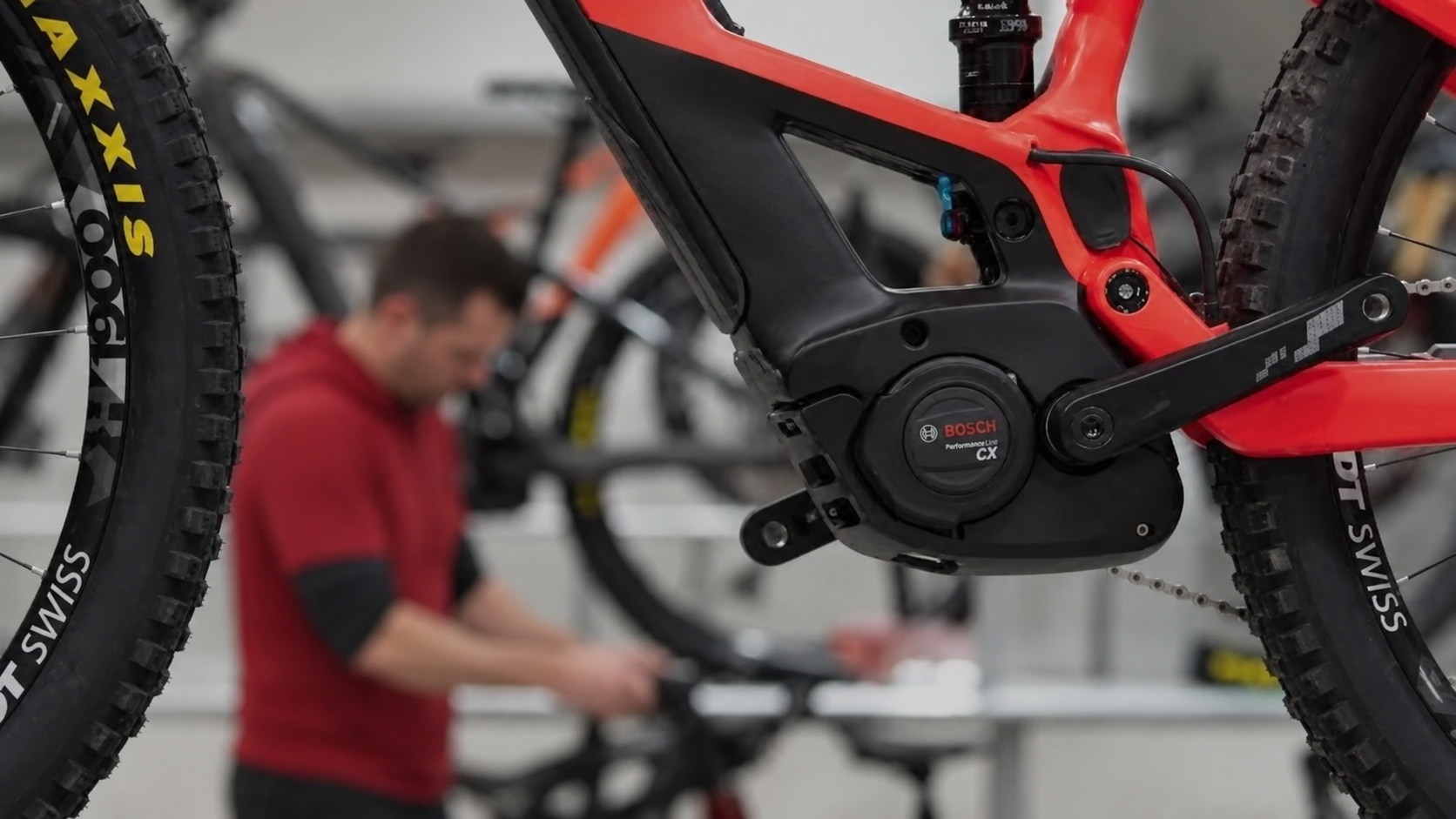 Close-up of a red electric mountain bike with a Bosch Performance Line CX motor and knobby tires in a bicycle workshop