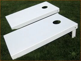 Two white cornhole boards with holes, placed on grass.