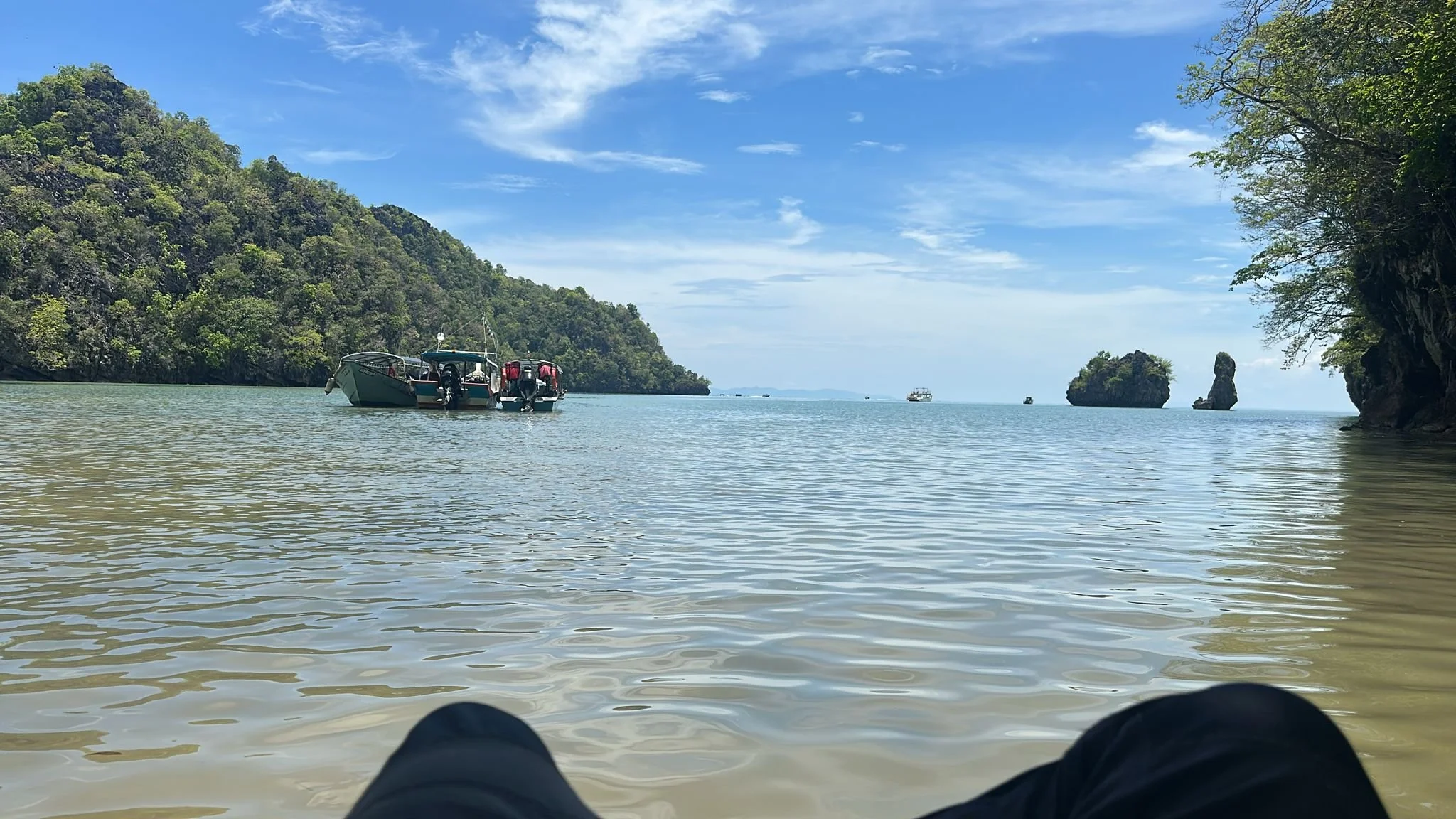 Team boat on calm water beside wooded islands