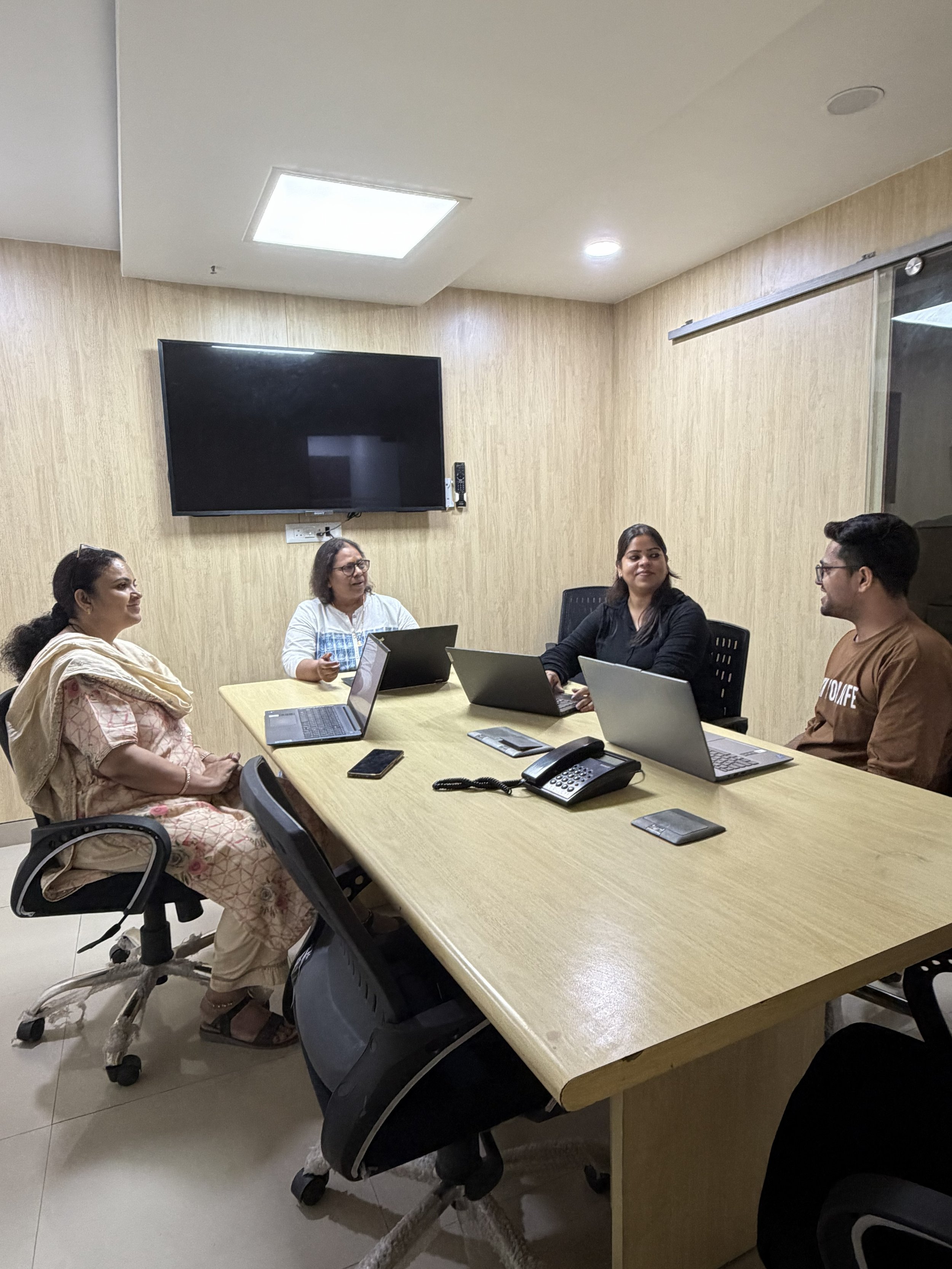 4 people in a conference room with laptops