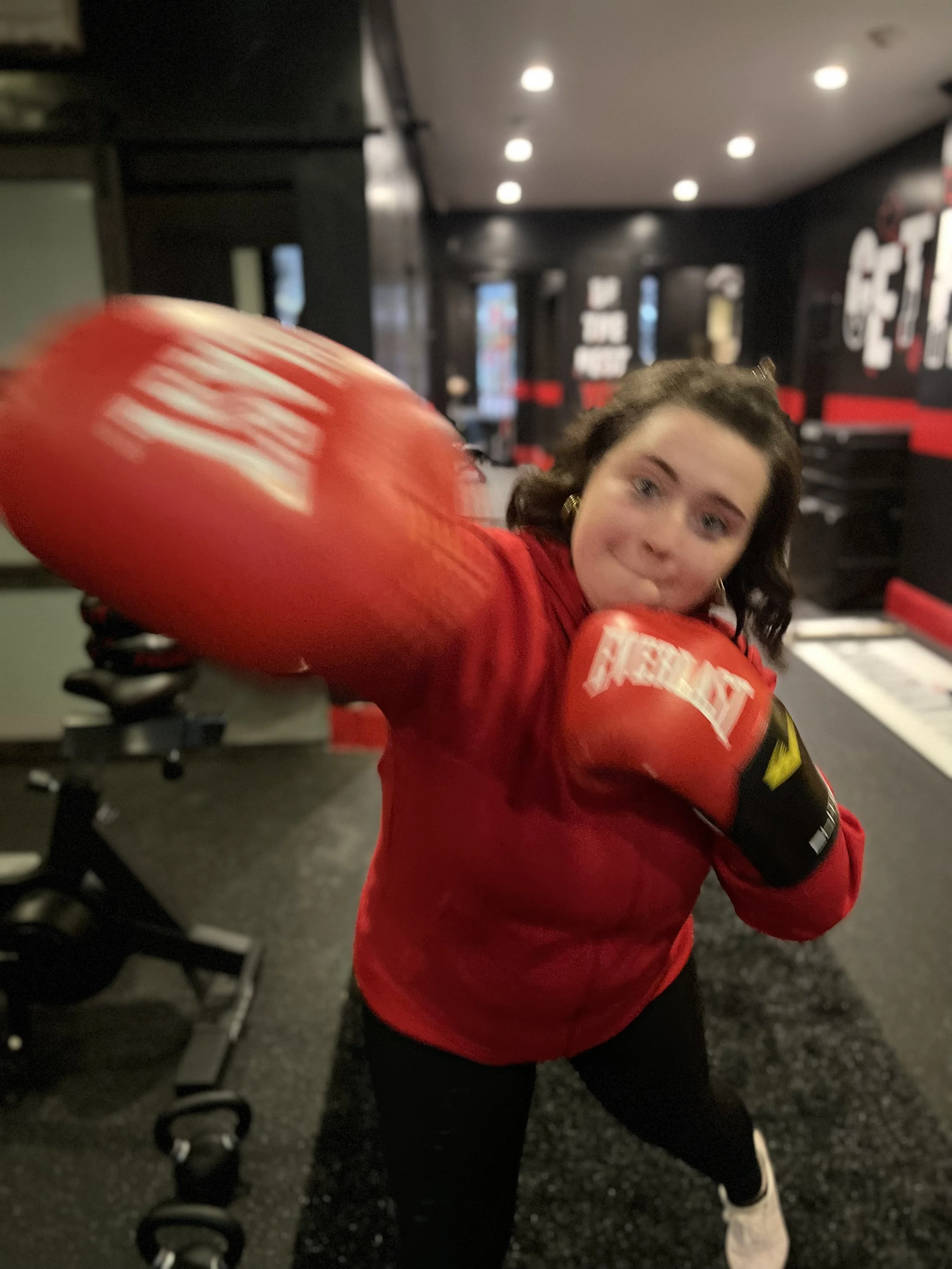 Person wearing red boxing gloves throwing a punch in a gym.