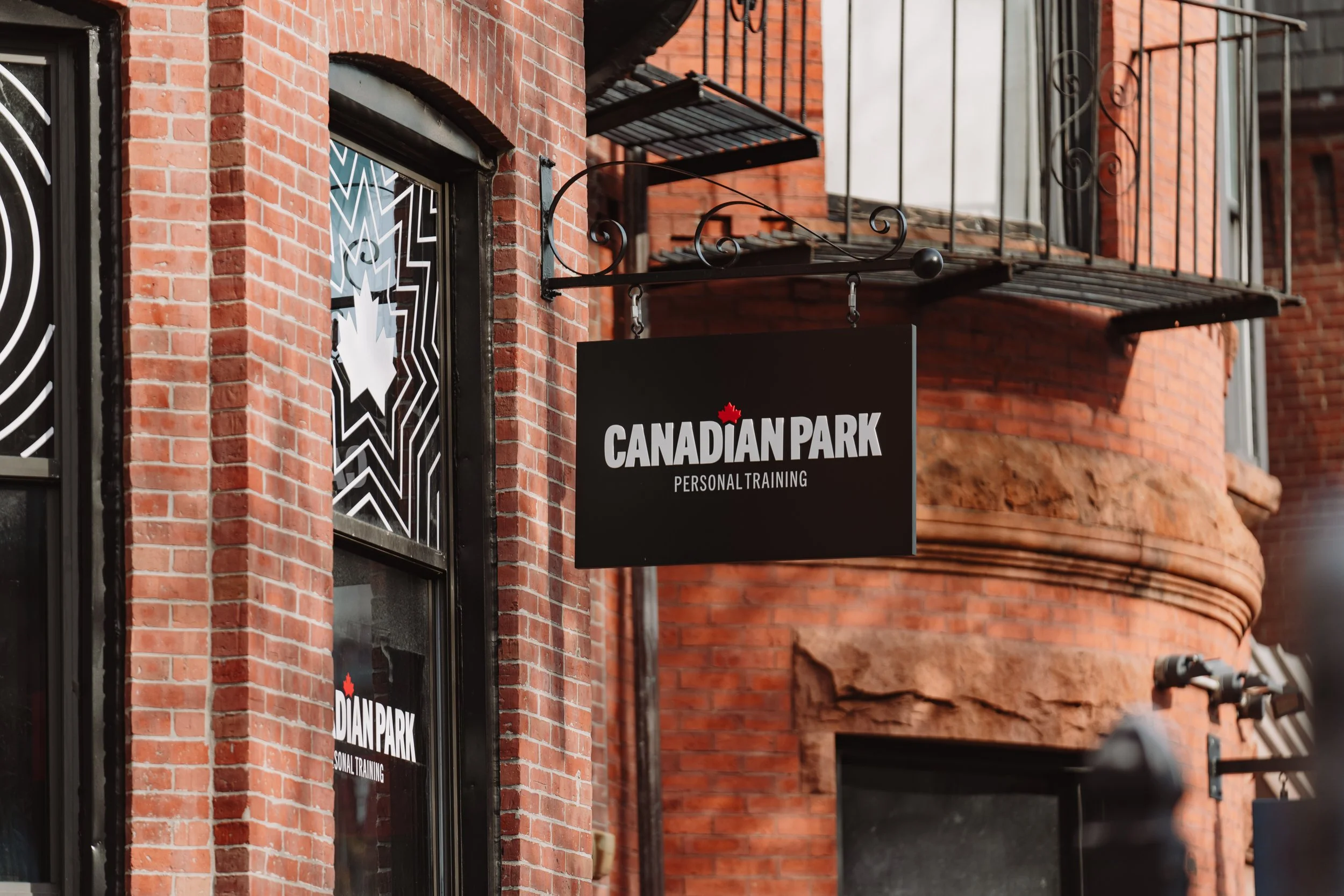 Sign for Canadian Park Personal Training hanging outside a brick building.
