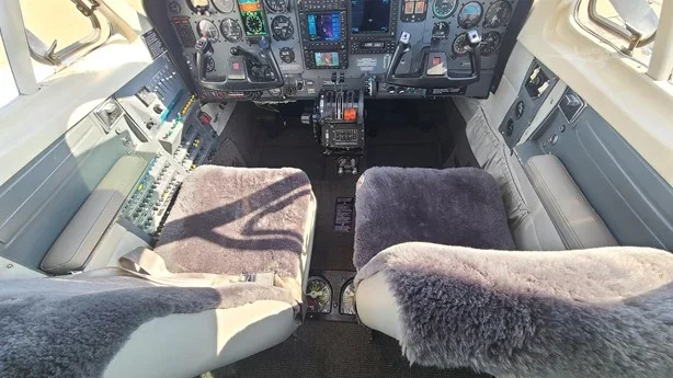 Interior view of an airplane cockpit with two pilot seats and flight instruments on the dashboard.