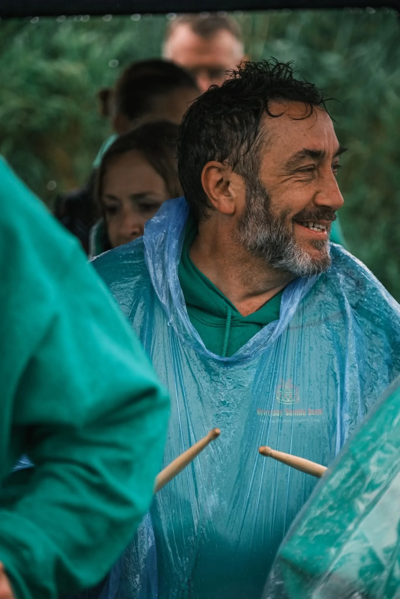 People smiling and arm wrestling inside a clear plastic rain poncho.
