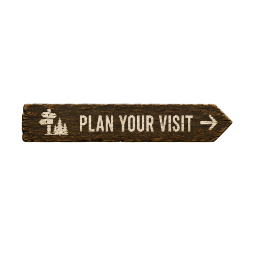 Wooden sign with white text and icon, saying "Plan Your Visit" with an arrow pointing to the right.