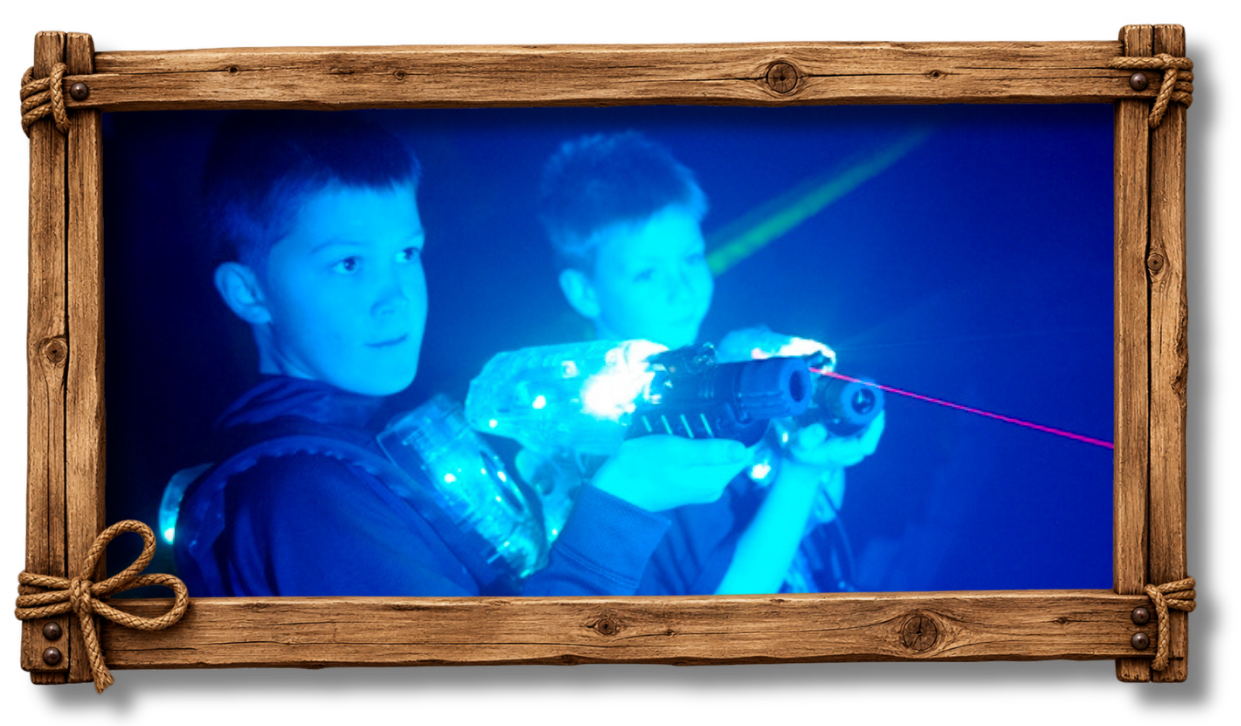Two boys playing laser tag, aiming laser guns with LED lights in a dark environment.