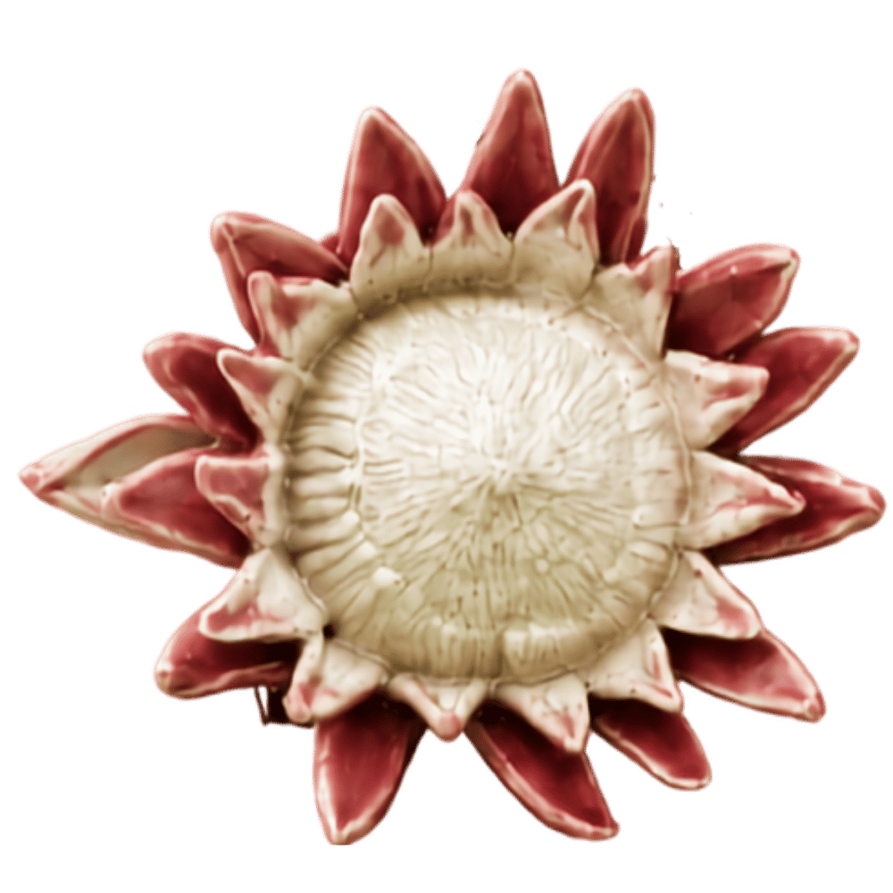 Ceramic sunflower-shaped sculpture with pink and white petals surrounding a textured cream-colored center.