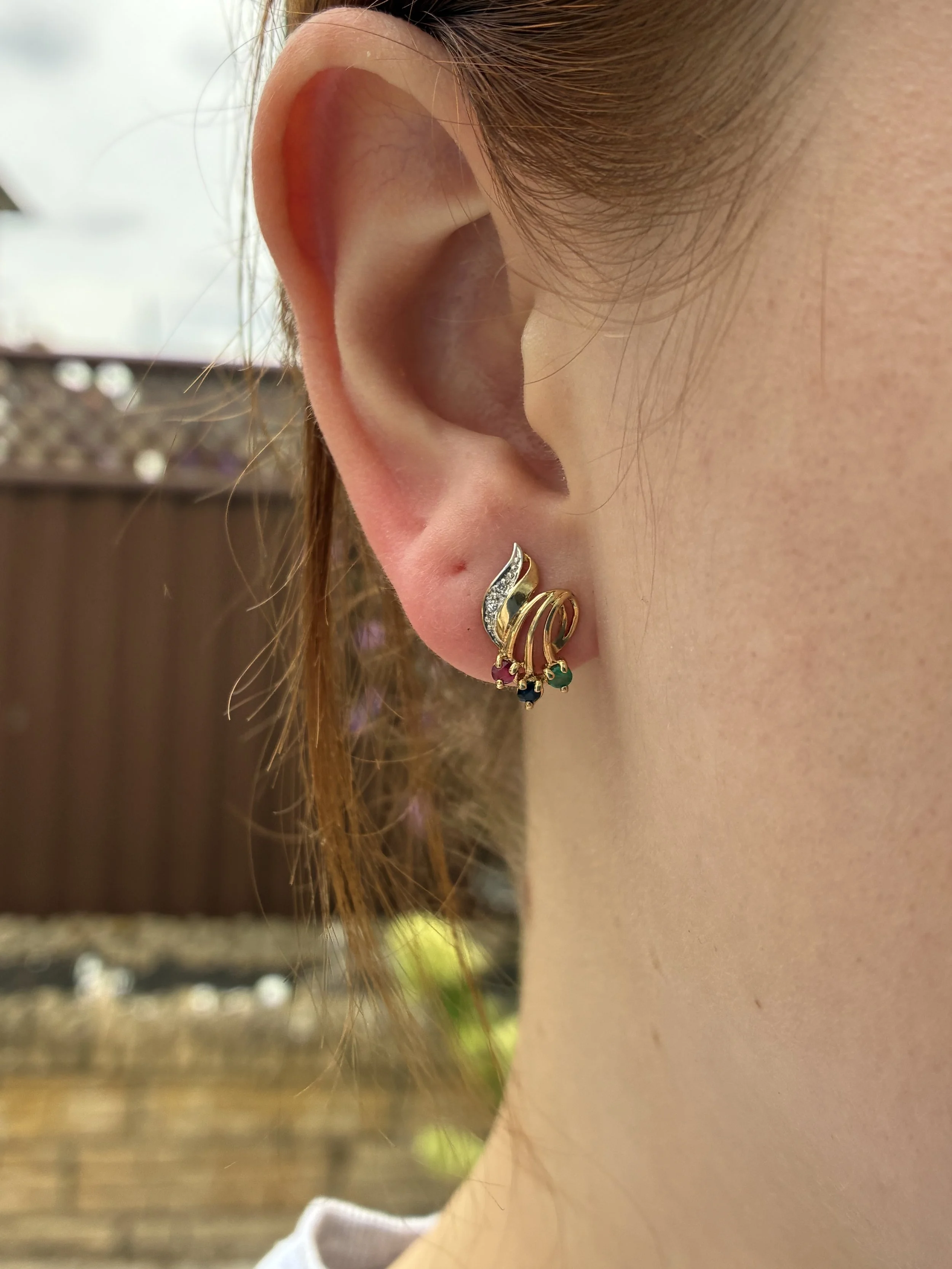 Multistone stud earring with sapphire, diamond and emerald in ear