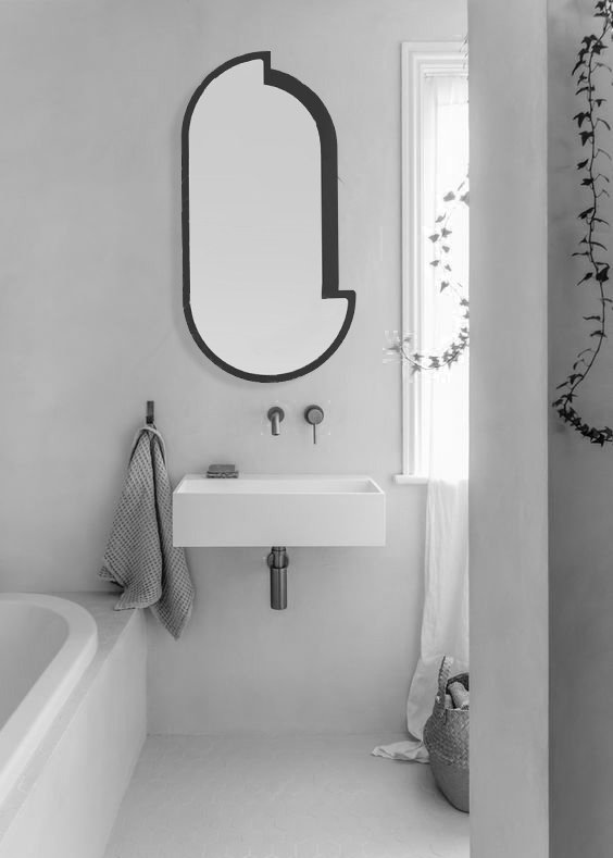 Salle de bain minimaliste en noir et blanc avec un miroir abstrait, une vasque blanche, un rideau de douche, un panier de rangement en tissu, et une fenêtre laissant entrer la lumière.