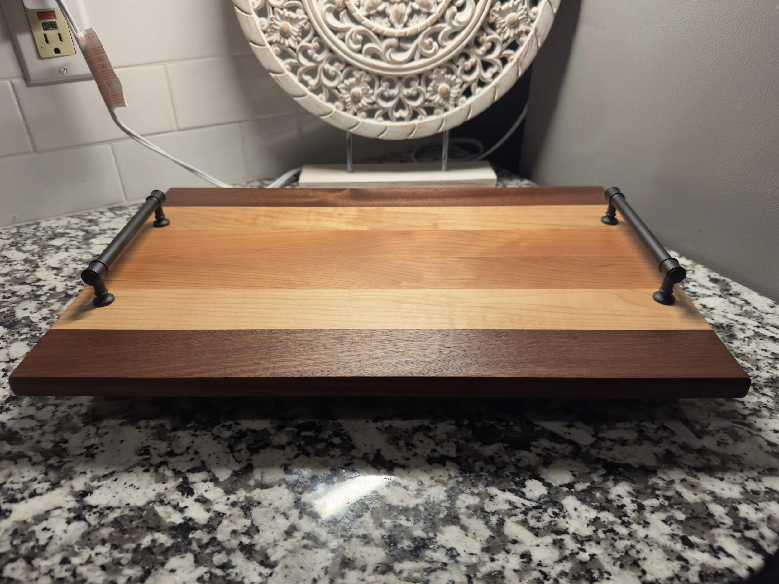 Striped wooden board fitted with black serving handles
