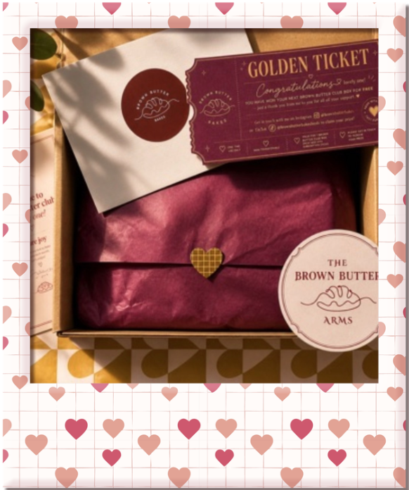 A gift box containing a brown paper bag, a gold ticket, and a circular sticker from The Brown Butter Arms with pink tissue paper.