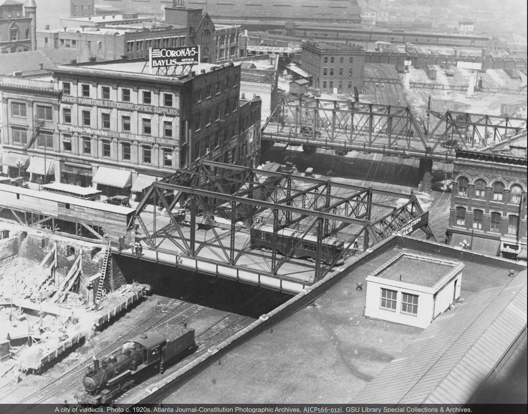 A city scene in 1920s Atlanta showing viaducts and train tracks, with buildings and construction in the background.
