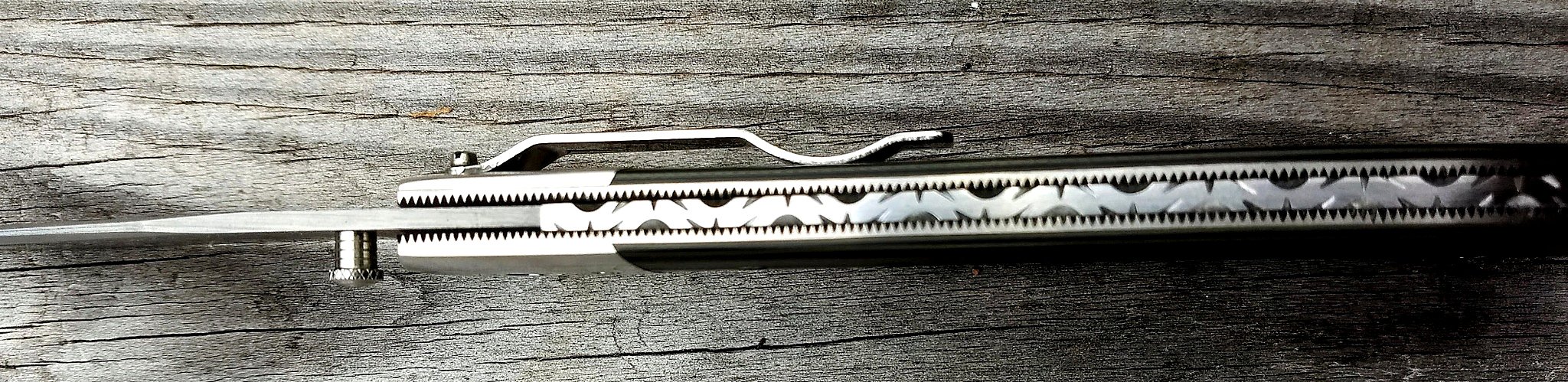 B.A. Dodson G-10 and titanium liner lock folder viewed from the spine, showing decorative backspacer file-work, liners, and pocket clip.