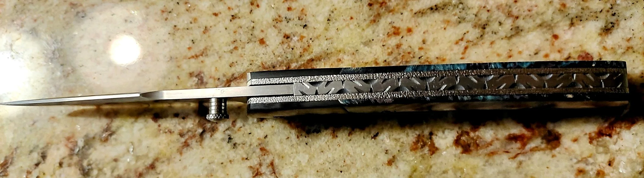 B.A. Dodson wood and resin liner lock folder viewed from the spine, showing decorative backspacer file-work, liners, and carbon fiber construction detail.